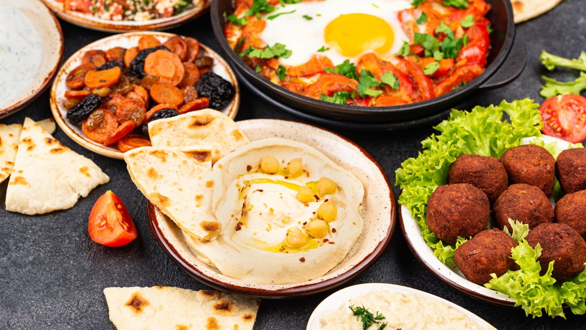 Middle Eastern spread with hummus, falafel, shakshuka, roasted vegetables, and pita bread